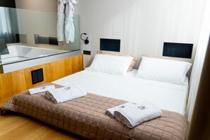 A hotel room with a bed, a large mirror, a built-in sink, and a bedside table. - Zoe luxury suites  (Catania)