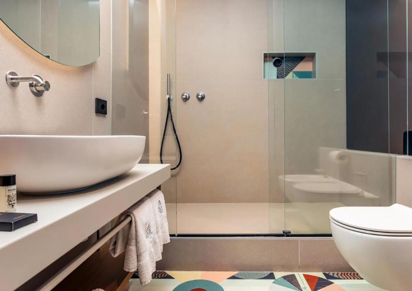 Une salle de bain moderne avec un grand lavabo blanc, une douche à parois de verre et des toilettes.