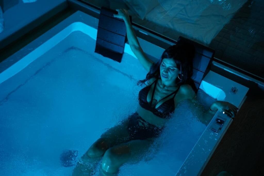 Une personne dans une baignoire, avec un panneau de commande à portée de main.