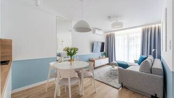 A modern living room with a sofa, dining table, and chairs.