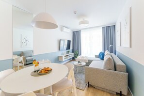 A modern living room with a dining table, sofa, and TV.