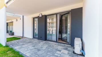 A modern building with a patio area, large sliding glass doors, and a small outdoor heater.