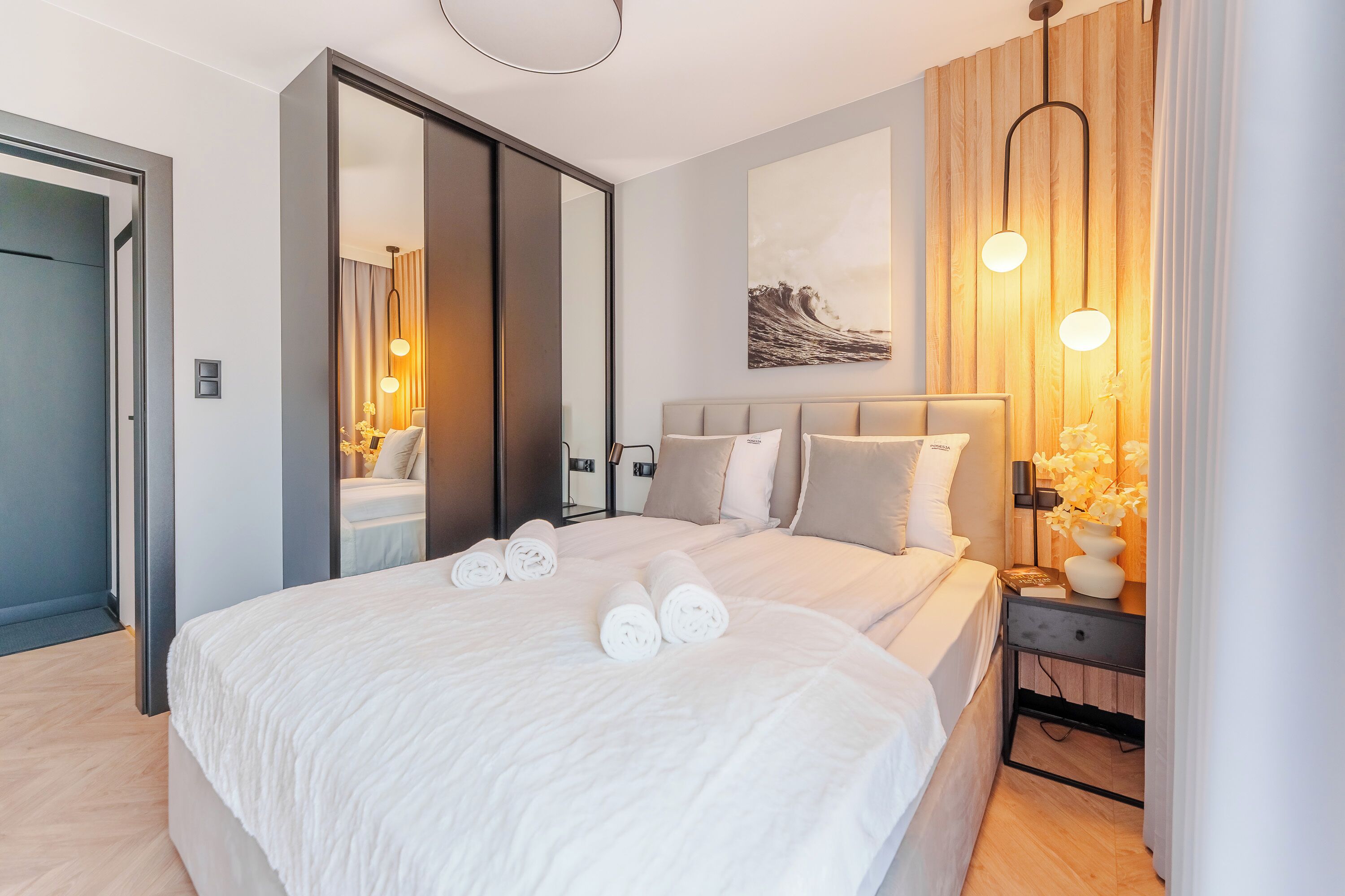 Camera d'albergo moderna con un letto grande, un comodino con una lampada e un'opera d'arte appesa al muro.