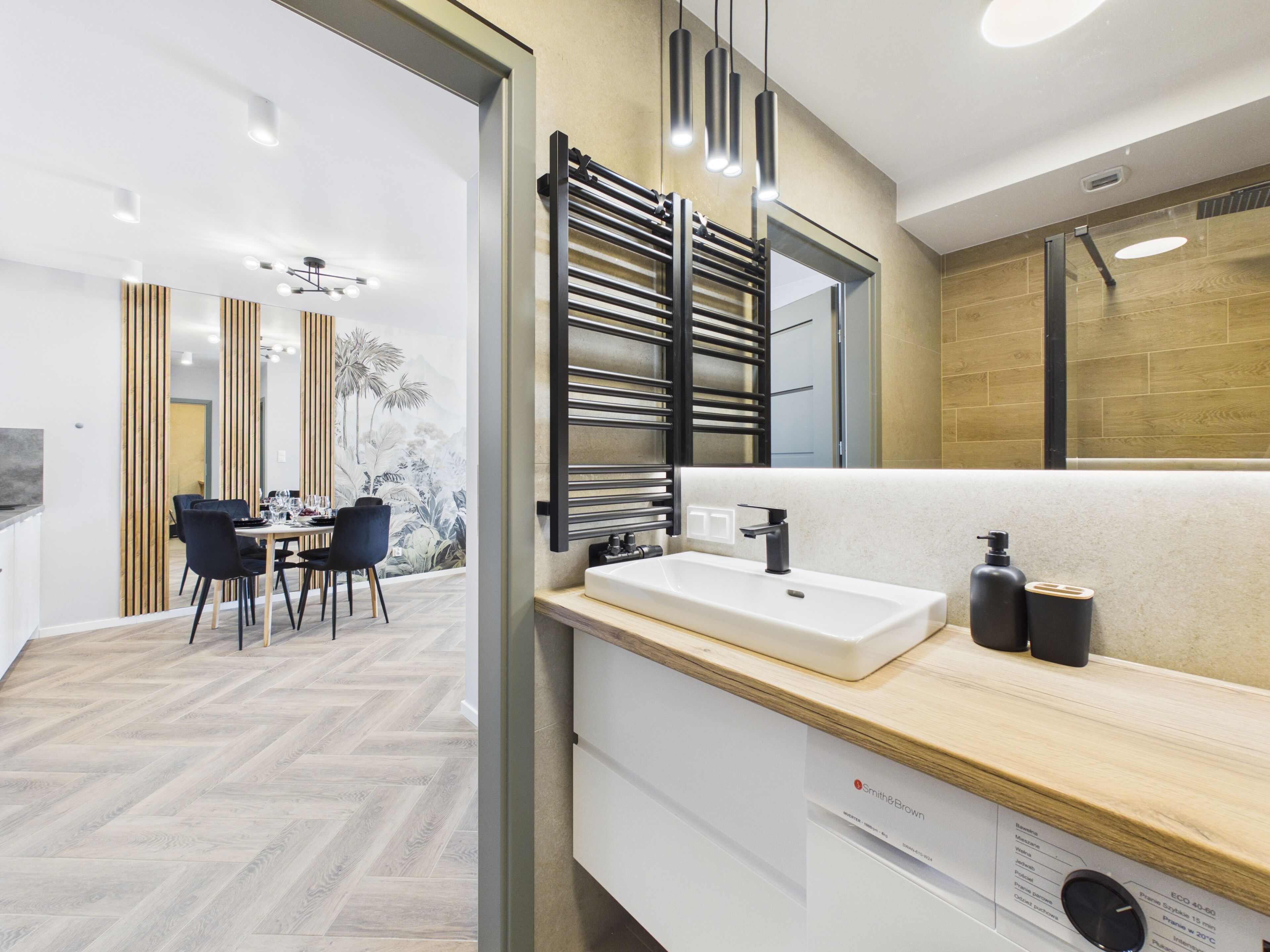 Un bagno moderno con uno specchio grande, un lavandino bianco e un porta asciugamani.