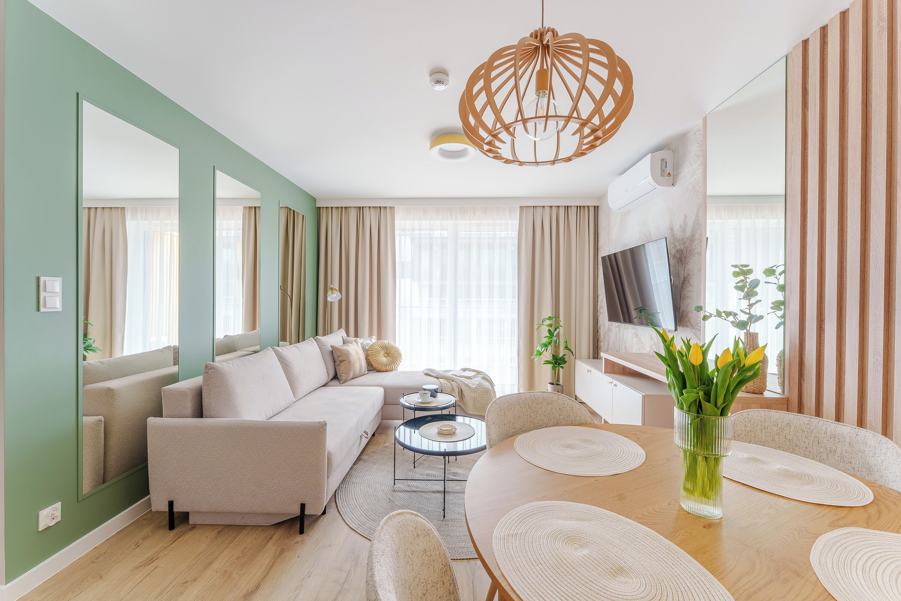 Una sala moderna con sofá, mesa de centro, mesa de comedor, sillas y televisor.