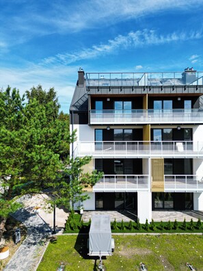Un edificio moderno a due piani con balconi, una zona esterna coperta e un piccolo veicolo al coperto.
