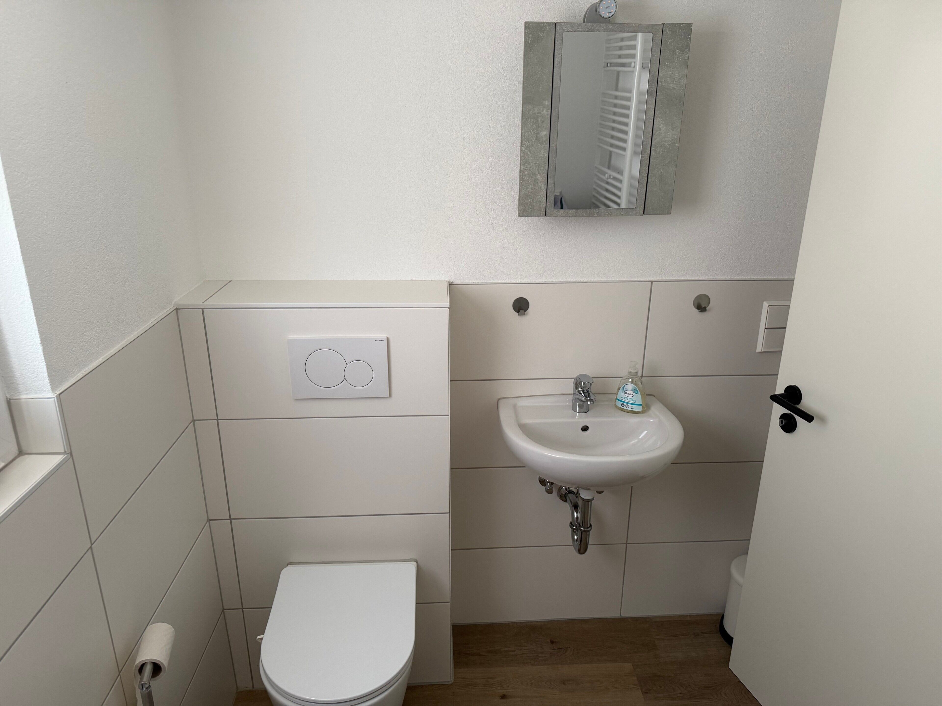 A small, clean bathroom with a toilet, sink, and a mirror.