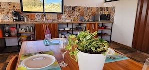 A kitchen with a dining table set for two, a coffee maker, a microwave, and a variety of dishes and utensils.
