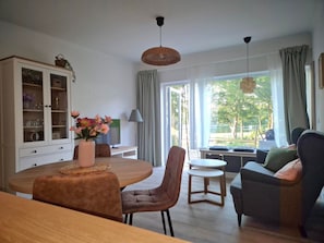 A modern living room with a dining area, large windows, and a view of the outdoors.