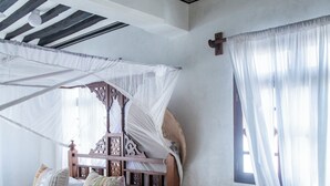 Un lit à baldaquin, une petite table et une fenêtre avec des rideaux.