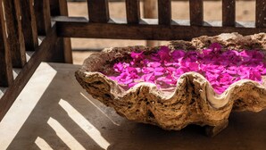 Une chaise en bois avec un récipient en pierre contenant des fleurs roses.