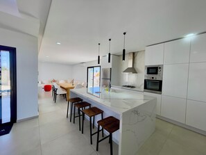 Eine moderne Küche mit Marmorarbeitsplatte, Edelstahlgeräten und einer Bar mit Hockern.