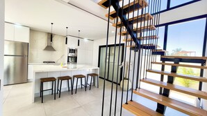 A modern kitchen with a central island, stainless steel appliances, and a wooden staircase. - Stunning home overlooking the ocean and the golf course (Djerba Midun)