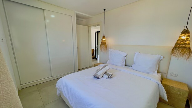 A hotel room with a large bed, a wardrobe, and two wall-mounted lamps. - Stunning home overlooking the ocean and the golf course (Djerba Midun)