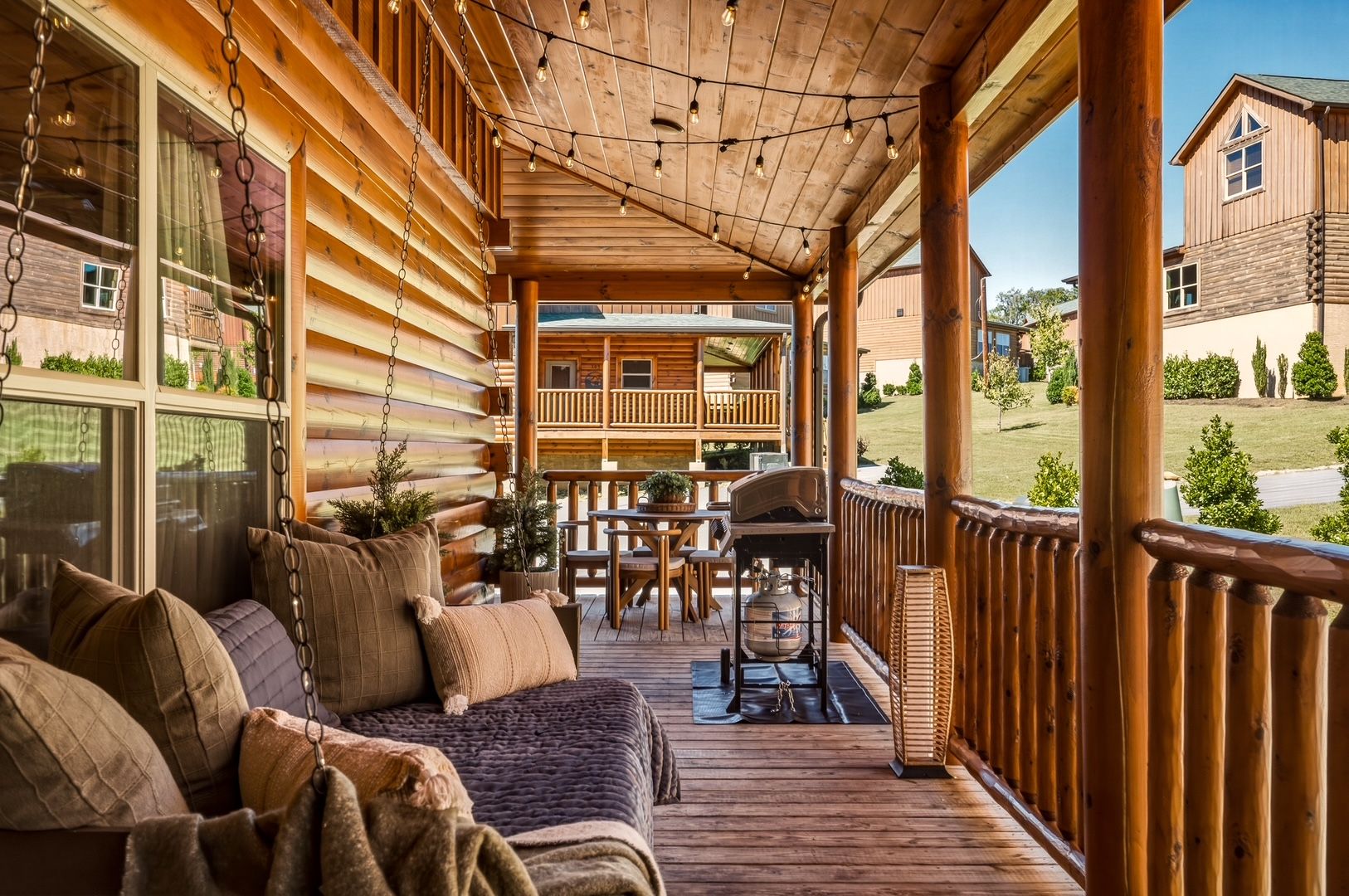 Une cabane en rondins dotée d’une véranda, d’un espace salon extérieur et offrant une vue sur le paysage environnant.