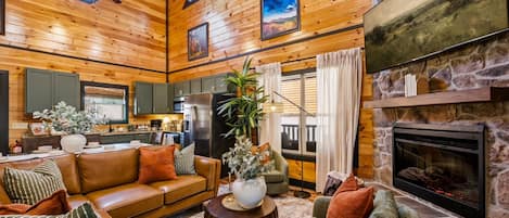 A cozy cabin interior with a living room, kitchen, and fireplace.