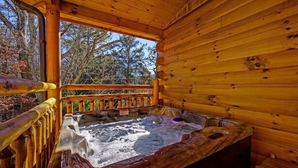Eine Holzhütte mit Whirlpool und einer Holzterrasse.