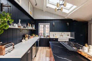 A modern kitchen with dark cabinetry, a white countertop, a gas stove, and a skylight. - Lavish Farmhouse With Lake Gardens Pool Table (Radstock)