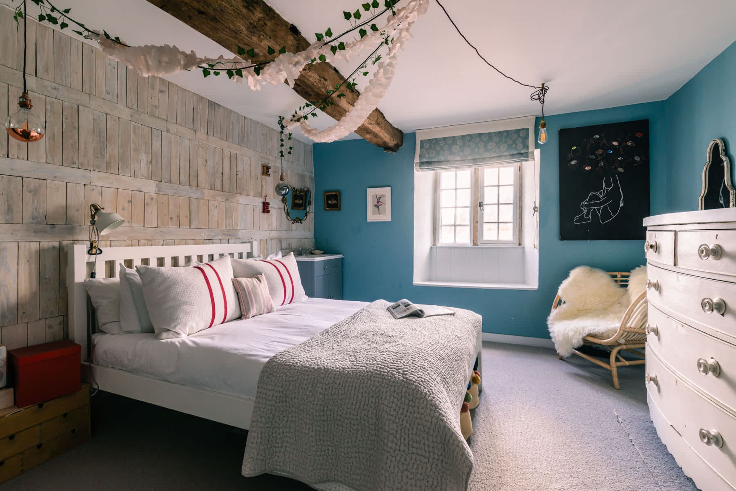 A bedroom with a bed, dresser, window, and wall decor.