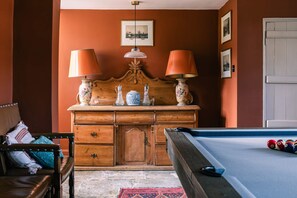 A room with a pool table, wooden cabinet with decorative items, and a framed picture on the wall. - Lavish Farmhouse With Lake Gardens Pool Table (Radstock)