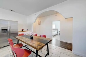 A modern kitchen with a stainless steel refrigerator, a dining table with red chairs, and a small potted plant. - Comfortable & Contemporary 3BR/2BA House - 5 Minutes to Downtown Austin (Austin)