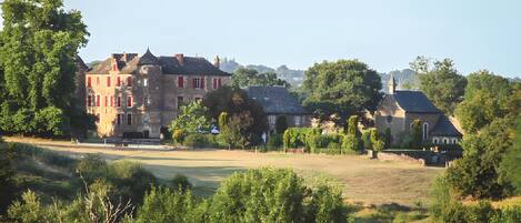 A large estate with multiple buildings, including a prominent red-roofed structure and a church with a spire.