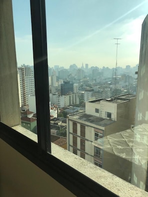 A view through a window of a cityscape with buildings of varying heights. - The Universe Executive Flat (São Paulo)