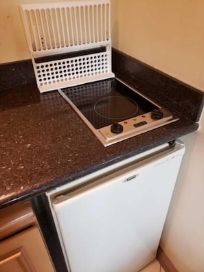 A compact kitchen with a built-in stove, a white refrigerator, and a countertop. - The Universe Executive Flat (São Paulo)
