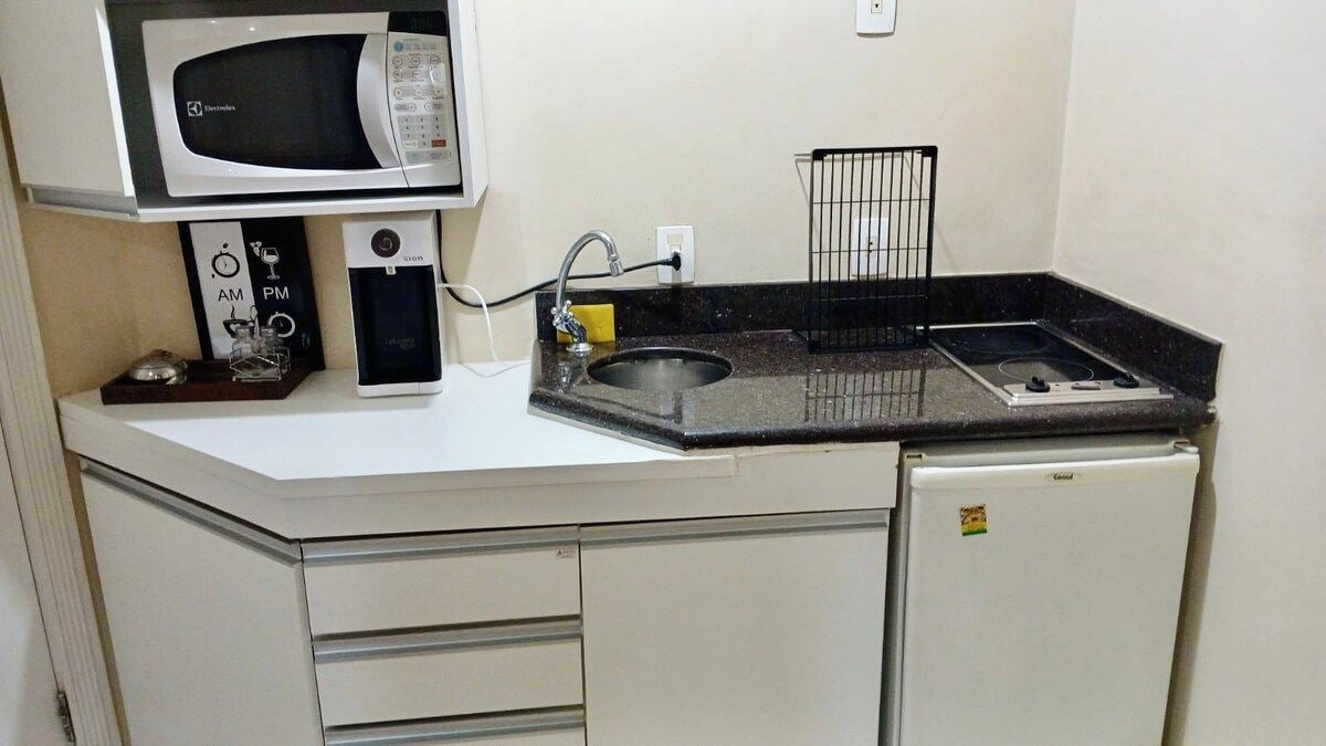 Una kitchenette compacta con microondas, estufa, pileta y refrigerador.