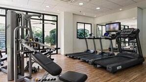 Un gimnasio con equipamiento de ejercicio, cintas de correr y un ventanal grande.