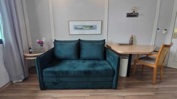 Una habitación con un sofá color aguamarina, una mesa de comedor de madera y una silla.