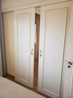 A set of white doors with a handle, leading to a room with a wooden floor. - The Universe Executive Flat (São Paulo)