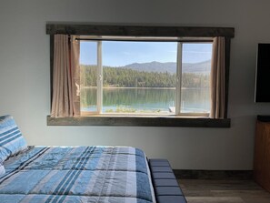 A bedroom with a large window overlooking a lake and forest. - HIDE-A-WAY SUITE RETREAT … Just Steps Away From shoreline on Bitterroot Lake (Marion)