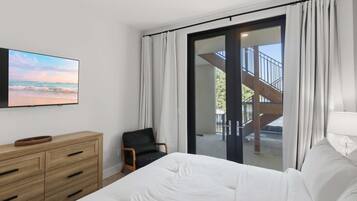 Un dormitorio con cama, cómoda de madera, silla, televisión y vistas al exterior.