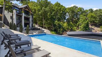 Ein modernes Gebäude mit Pool, Sitzgelegenheiten im Freien und einer natürlichen Kulisse.