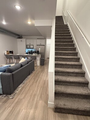A modern interior with a staircase, a kitchen area, and a seating area.