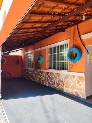 A covered outdoor area with a stone wall, a bicycle, and a tire hanging on the wall. - A very cozy house near the center of Belo Horizonte with a garage. (Belo Horizonte)
