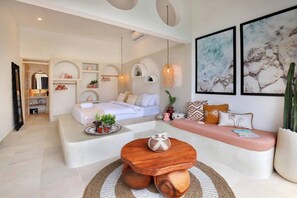 Ein modernes Wohnzimmer mit einer Couch, einem runden Couchtisch und einem Bett mit weißem Kopfteil.