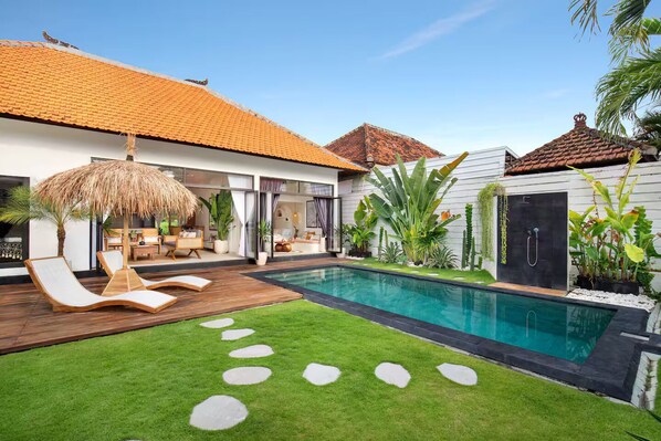 A modern house with a swimming pool, a thatched umbrella, and a well-maintained lawn. - 3 Bedroom Luxury Villa Blue Mango Umalas Canggu (Badung Regency)