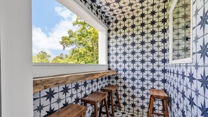 Une cuisine avec un dosseret décoré de motifs en étoile, des tabourets en bois et une fenêtre donnant sur un espace verdoyant.