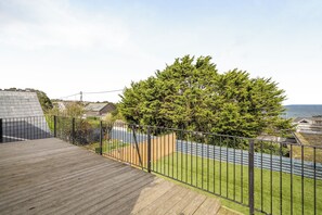 A residential property with a wooden deck, a metal fence, and a view of a tree and houses in the background. - 1 Bedroom Apartments Sleeps 3 - Balcony - Pets Ok (St Ives)