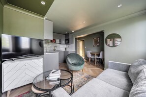 A modern living room with a flat-screen TV, a sofa, a coffee table, and a dining area with chairs and a table. - 1 Bedroom Apartments Sleeps 3 - Balcony - Pets Ok (St Ives)