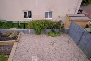 A residential backyard with a gravel area, a wooden raised bed, and a wooden fence. - 1 Bedroom Apartments Sleeps 3 - Balcony - Pets Ok (St Ives)