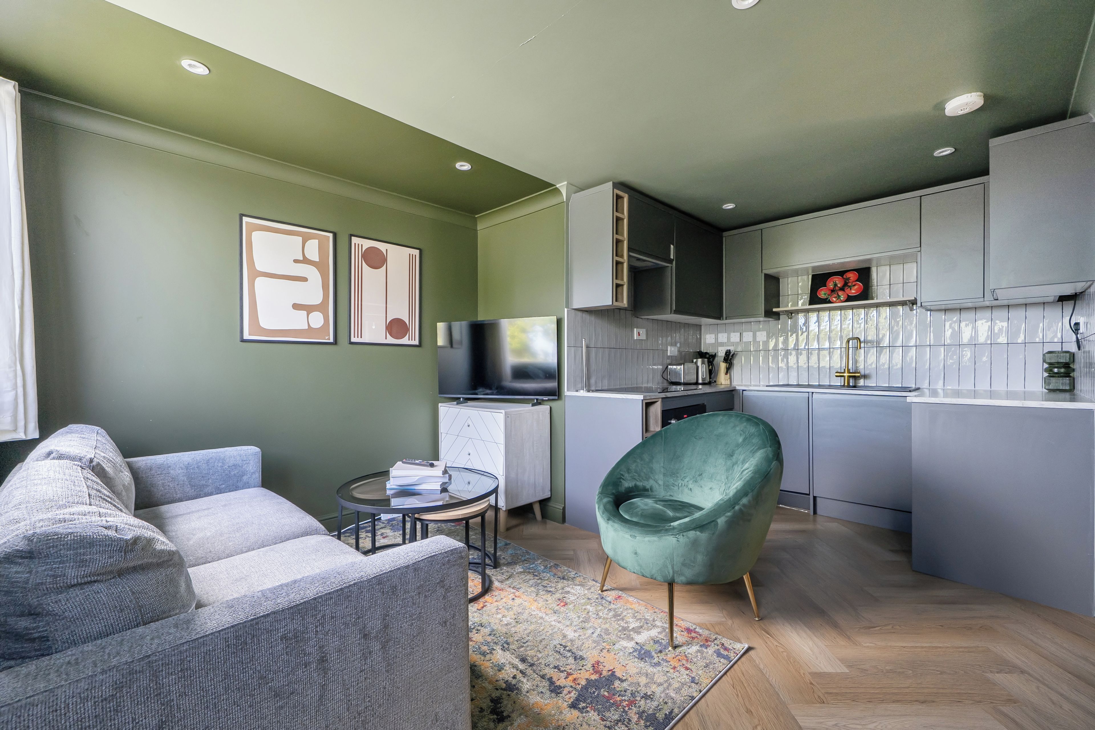 A modern living room with a grey sofa, a green armchair, a small coffee table, and a flat-screen TV.