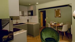 Et moderne køkken med en central ø, et spiseområde med et rundt bord og stole, samt en trappeopgang til en etage ovenpå.