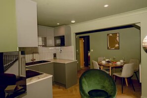 A modern kitchen with a central island, a dining area with a round table and chairs, and a staircase leading to an upper level. - 1 Bedroom Apartments Sleeps 3 - Balcony - Pets Ok (St Ives)