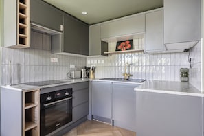 A modern kitchen with grey cabinetry, a Bosch oven, and a sink with a gold faucet. - 1 Bedroom Apartments Sleeps 3 - Balcony - Pets Ok (St Ives)