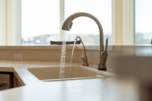 Uma pia de cozinha com uma torneira moderna e uma janela ao fundo.
