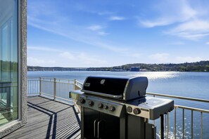 Ein Grill auf einer Terrasse mit Blick auf einen Fluss und sanfte Hügel in der Ferne.