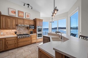Una cocina moderna con armarios de madera, electrodomésticos de acero inoxidable, una isla grande y vista al agua.